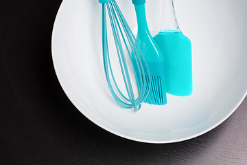 Image showing Green silicone pastry brush and soup plate isolated on black