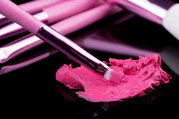 Image showing lipstick with a brush make-up on black 