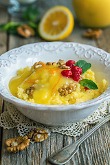 Image showing Tasty millet porridge with lemon cream and nuts for breakfast.
