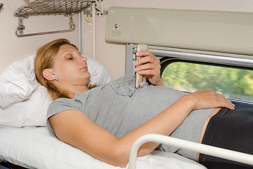 Image showing Passenger train is on the top shelf of the side seats in the second-class carriage and looking at the phone