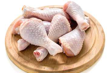 Image showing Raw chicken drumsticks on a wooden board.