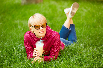 Image showing Beautiful young woman enjoys drinking coffee and lying on the grass