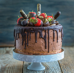 Image showing Chocolate cake with strawberries, wafer rolls and candies.