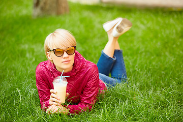 Image showing Beautiful young woman enjoys drinking coffee and lying on the grass