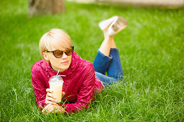 Image showing Beautiful young woman enjoys drinking coffee and lying on the grass