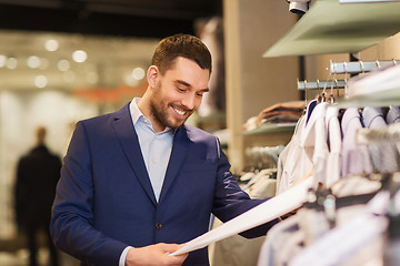 Image showing happy young man choosing clothes in clothing store