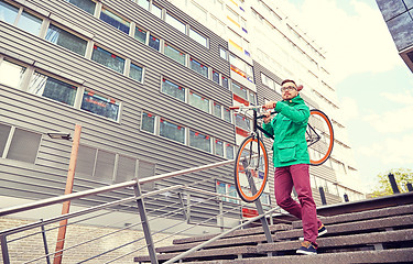 Image showing young hipster man carrying fixed gear bike in city