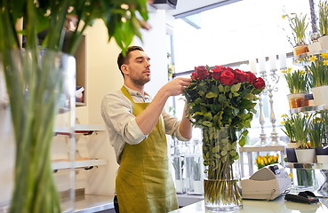 Image showing smiling florist man with roses at flower shop