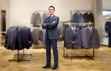 Image showing happy businessman in suit over clothing store