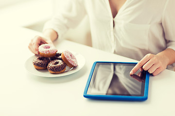 Image showing close up of hands with tablet pc and donuts