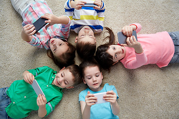 Image showing happy children with smartphones lying on floor