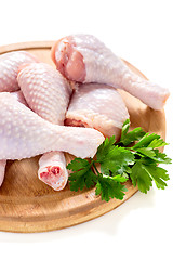 Image showing Chicken drumsticks and parsley on a wooden board.
