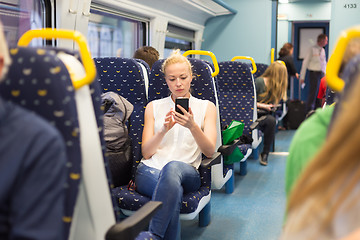 Image showing Woman using mobile phone while travelling by train.