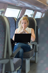 Image showing Woman travelling by train working on laptop.