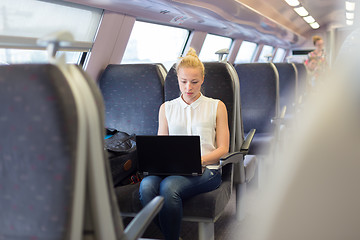 Image showing Woman travelling by train working on laptop.