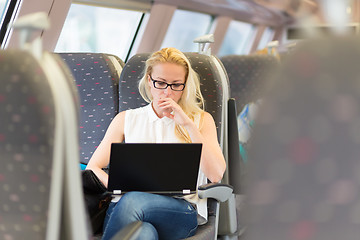 Image showing Woman travelling by train working on laptop.