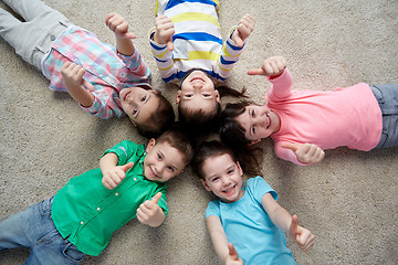 Image showing happy kids lying on floor and showing thumbs up