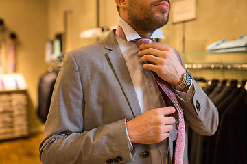 Image showing close up of man tying tie at clothing store