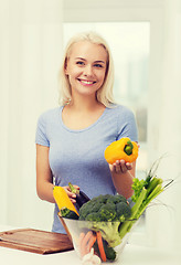 Image showing smiling young woman cooking vegetables at home