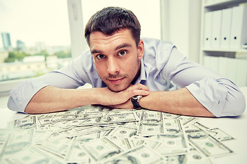 Image showing happy businessman with heap of money in office