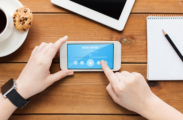 Image showing close up of woman with smartphone on wooden table