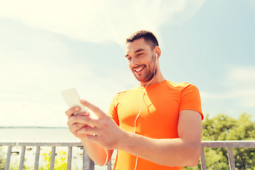 Image showing smiling young man with smartphone and earphones