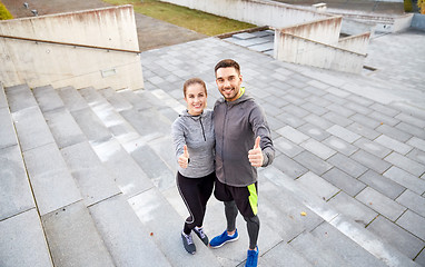 Image showing smiling couple showing thumbs up on city street