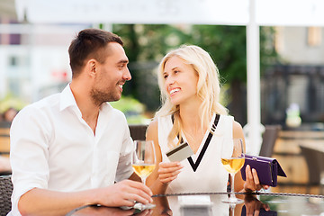 Image showing happy couple with bank card and bill at restaurant