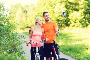 Image showing couple with bicycle and smartphone selfie stick