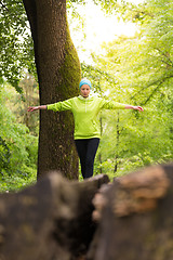 Image showing Woman holding balance on tree trunk in nature.