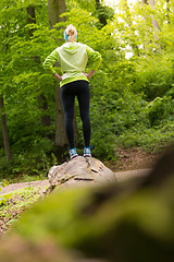 Image showing Woman standing on tree trunk in nature.