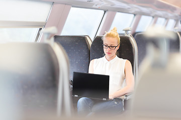 Image showing Woman travelling by train working on laptop.