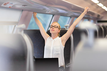 Image showing Woman streching while travelling by train.