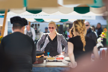 Image showing Woman buying meal at street food festival.