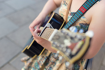 Image showing Female street musician playing guitar.