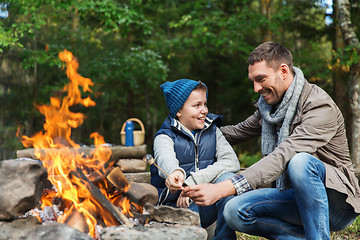 Image showing father and son roasting marshmallow over campfire