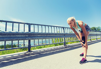 Image showing young woman with injured knee or leg outdoors