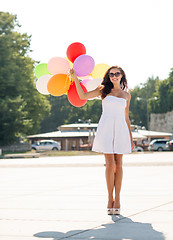 Image showing smiling young woman in sunglasses with balloons