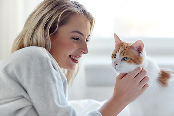 Image showing happy young woman with cat in bed at home