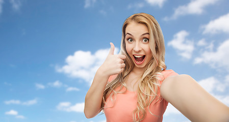 Image showing happy woman taking selfie and showing thumbs up