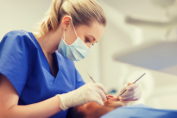 Image showing female dentist checking up male patient teeth