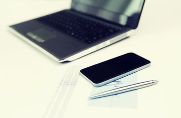 Image showing close up of smartphone, laptop and pen on table