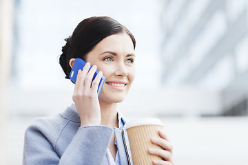 Image showing smiling woman with coffee calling on smartphone