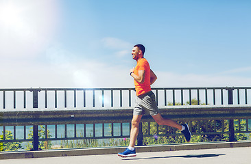 Image showing smiling young man running at summer seaside