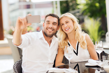 Image showing happy couple taking selfie with smatphone at cafe