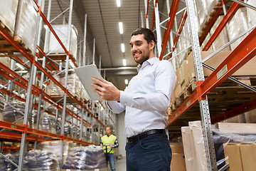 Image showing happy businessman with tablet pc at warehouse