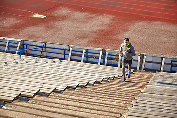 Image showing happy young man running upstairs on stadium