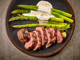 Image showing portion of sliced beef steak and asparagus