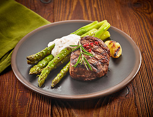 Image showing grilled beef steak and asparagus on dark plate