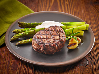 Image showing grilled beef steak and asparagus on dark plate